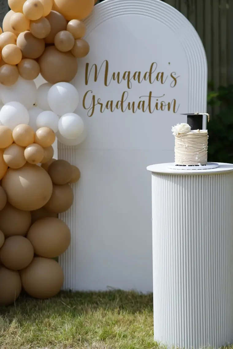 Girlanda z balonów w beżach i bieli nad stołem z tortem, dekoracja jasna i stonowana